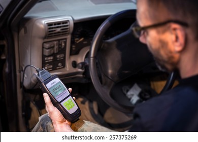 Mechanic making car diagnostics using obd device. OBD is On Board Diagnostics, an electronics self diagnostic system, typically used in automotive applications