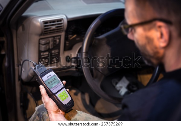Mechanic making car\
diagnostics using obd device. OBD is On Board Diagnostics, an\
electronics self diagnostic system, typically used in automotive\
applications