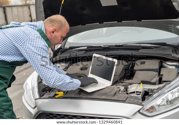 Mechanic making\
diagnostic of a car with\
laptop