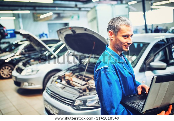 mechanic man with automotive
diagnostic scanner and clipboard checking car system at
workshop
