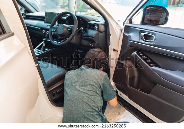 Mechanic man checking and installing\
dash cam device with wire inside a car at workshop\
garage