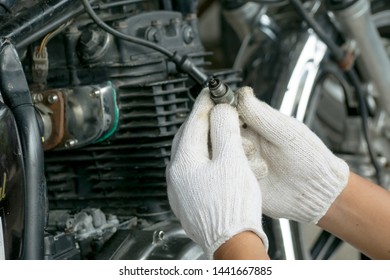 Mechanic man checking a spark plug of vintage motorcycle. Garage service. Repair. Maintenance and fixing concept. - Powered by Shutterstock