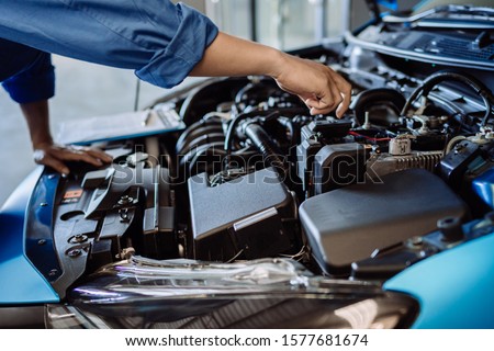 Mechanic man examining and maintenance to customer the engine a vehicle car hood, Safety inspection test engine before customer drive on a long journey, transportation repair service center