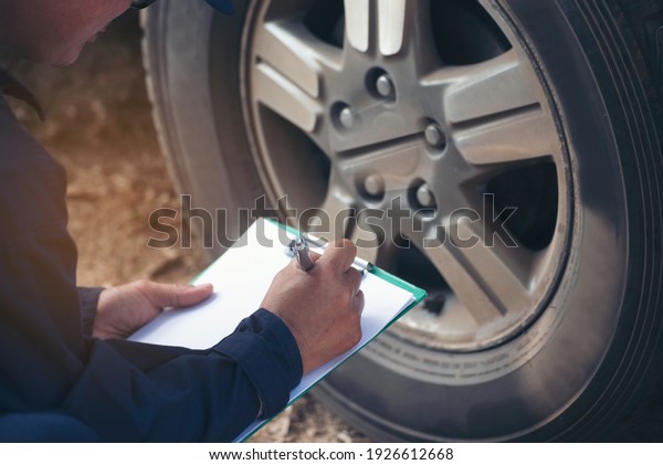 Mechanic man hands checking car tires outdoor on\
site service auto garage for automotive mobile center services.\
Technician workshop repair checking tyres car motor vehicles\
service mechanical\
hands