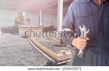 Mechanic man hold  spanner tool for industrial maintenance and repair bulldozer in power plant
