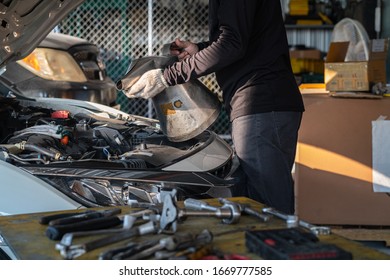 Mechaniker, der den Öltrichter hält, um Motoröl in der Reparatur- und Wartungsgarage zu füllen