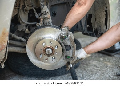 Mechanic man installing new brake disc and brake pads on car, car repair - Powered by Shutterstock