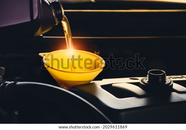 Mechanic man pouring lubricant oil to car engine\
in the repair garage