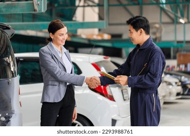 Mechanic man shaking hands with customer at the repair garage. Auto mechanic shaking hands with young woman client, Car repair and maintenance concepts - Powered by Shutterstock