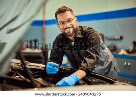 Mechanic man smiling for the camera while working at the car repair service.