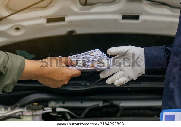 Mechanic man takes cash as payment from\
customer.after finish checking car system.Professional\
service.checking the opened hood car.Repair\
service.
