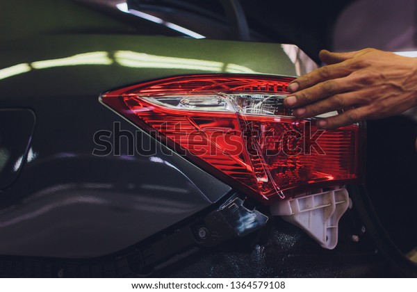 mechanic matching automobile headlight lamp to\
damaged car at repair service\
station.