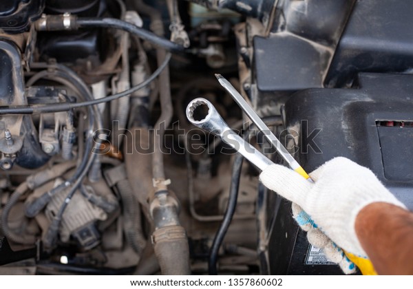 mechanic men with\
wrench repairing car engine at workshop - auto service, repair,\
maintenance and people\
concept.