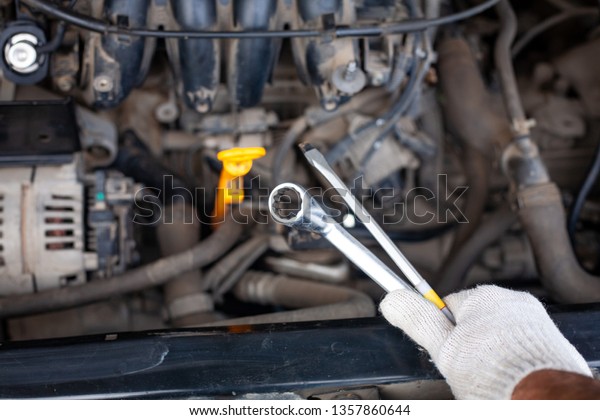 mechanic men with\
wrench repairing car engine at workshop - auto service, repair,\
maintenance and people\
concept.