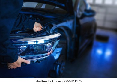 Mechanic with new car headlight in a workshop - Powered by Shutterstock