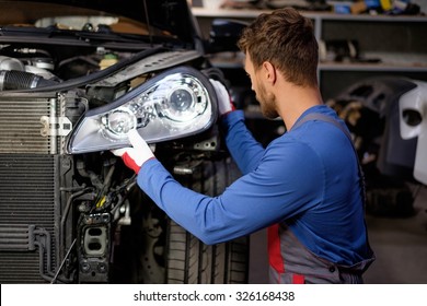 Mechanic With New Car Headlight In A Workshop