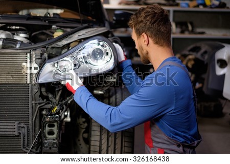 Mechanic with new car headlight in a workshop