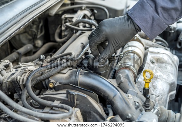 mechanic is opening the oil cap for change of oil\
from a car engine. auto\
service