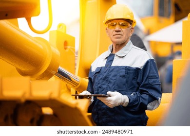 Mechanic operator with tablet computer check hydraulic piston of hose system equipment on excavator. Industry engineer of machinery tractor.