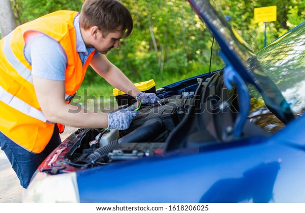 Mechanic in an orange vest with a diagnostic tablet\
checks the car engine. scheduled maintenance and diagnostics of the\
car engine. Mechanic With Digital Tablet Showing Graph While\
Examining Car