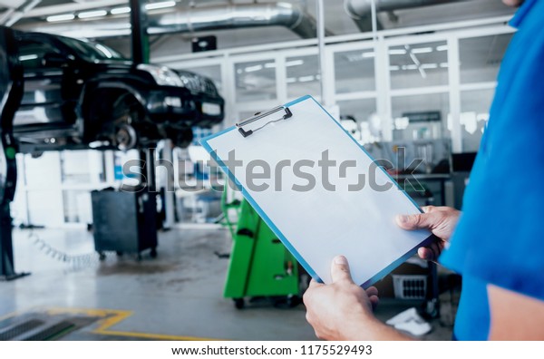 Mechanic with a order board at the service\
station. Background auto\
service