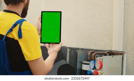 Mechanic ordering new components on green screen mock up tablet for out of order air conditioner after finishing troubleshooting. Expert looking online for hvac system replacement parts - Powered by Shutterstock - Get 15% off with code: PIKWIZARD15