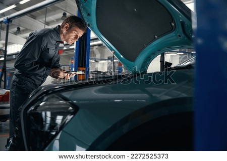 Mechanic in overalls working near the car
