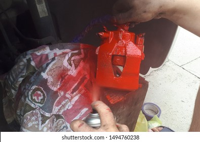 The mechanic paints the brake caliper red.