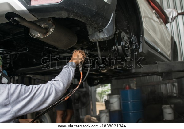 The mechanic paints  suspension carr with a paint\
gun.  Rust spray