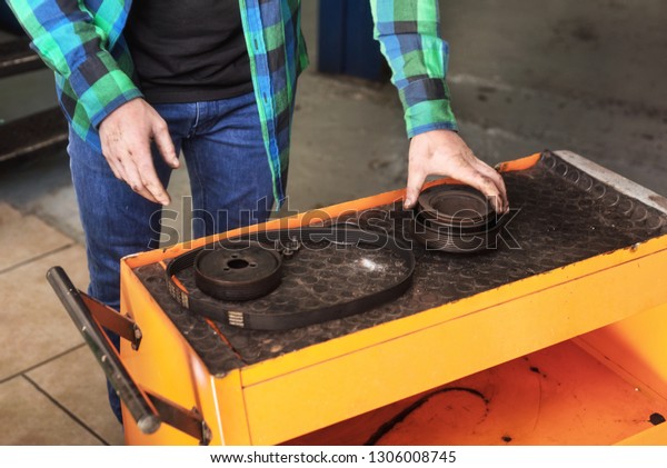 Mechanic picking\
up a gear from working table\
.