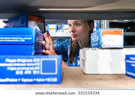 Mechanic picking up spare parts in boxes from a storage rack in a supply room