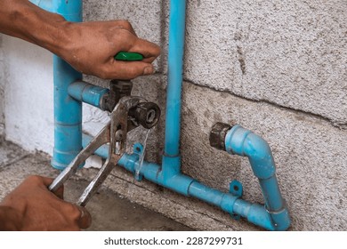 A Mechanic Plumber is Repairing a Leaking Water Pipe Tap Near the Water Meter.