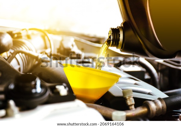 Mechanic pouring motor oil to engine in the repair\
garage shop