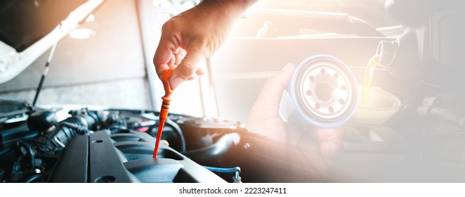 The mechanic is pulling the lube dipstick and oil filter in the hand with oil pouring to engine, double exposure on background, auto maintenance service concept