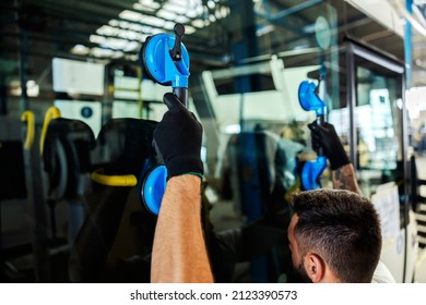 A Mechanic Putting On Window On A New Bus At Workshop.