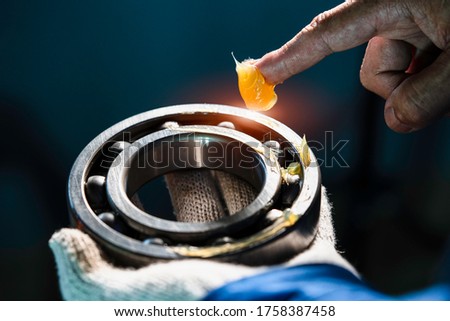 Mechanic is putting yellow grease in the into bearing, engineering and industrial concept
