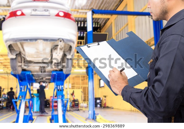 Mechanic recording a clipboard of service\
order for maintaining car at the repair\
shop