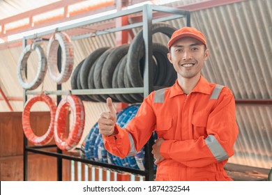 mechanic in red wearpack with thumbs up while in the workshop with a tire rack background - Powered by Shutterstock