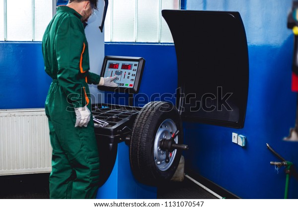 Mechanic removes\
car tire and balancing\
wheels