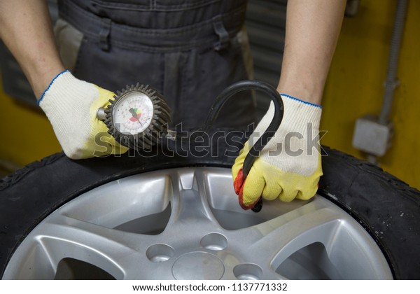 Mechanic removes car tire closeup. Machine for\
removing rubber from the wheel\
disc
