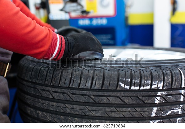 Mechanic removes car tire closeup. Machine for\
removing rubber from the wheel\
disc