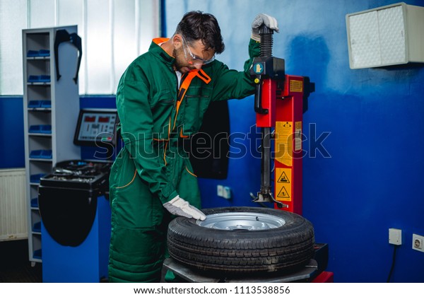 Mechanic removes car tire  Machine for removing\
rubber from