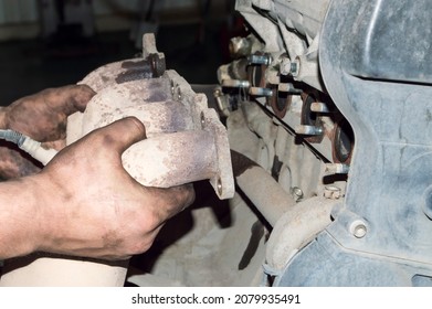 A mechanic removes the exhaust manifold from an automobile internal combustion engine in an auto repair shop - Shutterstock ID 2079935491