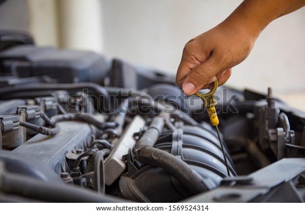 Mechanic repairing car, mechanic\
checking level car motor oil with open hood.\
closs up hand\
mechanic holding dipstick check car engine oil for\
maintenance.