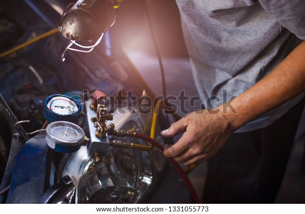 Mechanic repairing a car,Check car air\
conditioning system refrigerant recharge,Auto mechanic Worker hands\
holding and point to monitor to check and fixed car air conditioner\
system in car service.