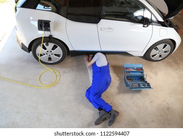 Mechanic Repairing An Electric Driven Car In Garage