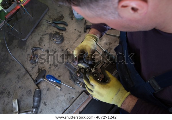 Mechanic repairing electric generator, repair of\
starter \
