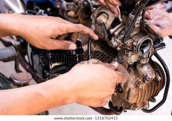 The mechanic is repairing the engine and cleaning\
the spare parts.