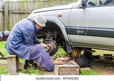 The Mechanic Is Repairing The Front Suspension Of The Car At Home. Car Repair Is A Service Station Environment.