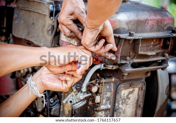 A mechanic is repairing\
a tractor used in agriculture. Drain the old oil from the engine.\
Copy space.